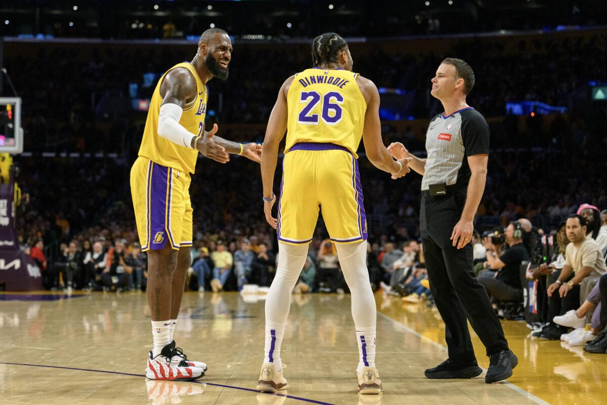 Los compañeros de los Lakers, LeBron James, izquierda, y Spencer Dinwiddie discuten una decisión con un árbitro.