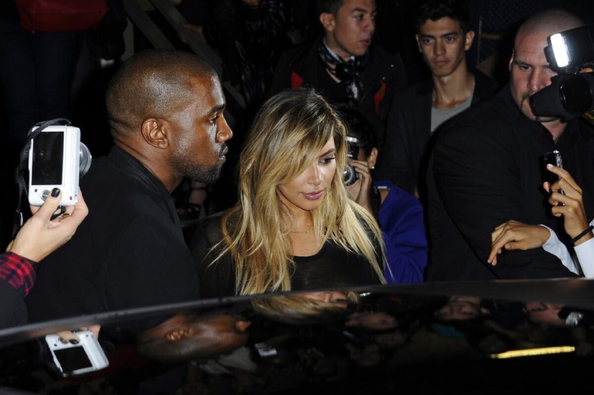 Kanye West, left, and Kim Kardashian leave after attending a Givenchy show at Paris Fashion Week.