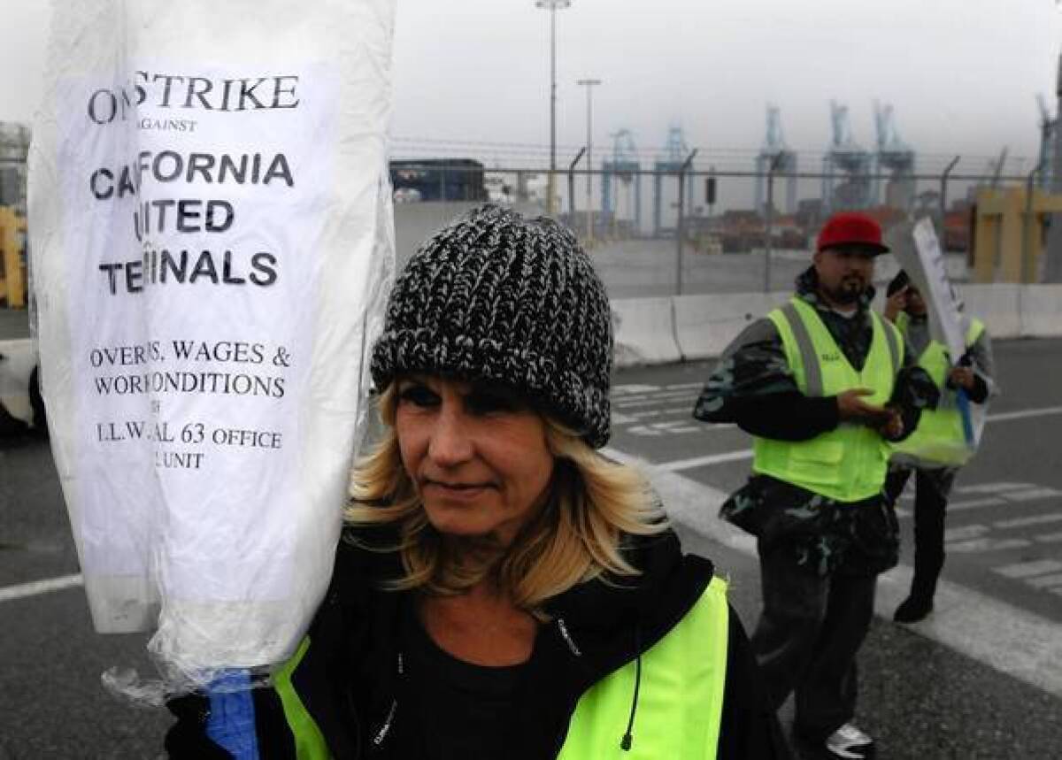 A clerical workers union member walks a picket line at the Port of Los Angeles. Other unions are honoring the picket lines at the ports of Los Angeles and Long Beach, virtually shutting them down.