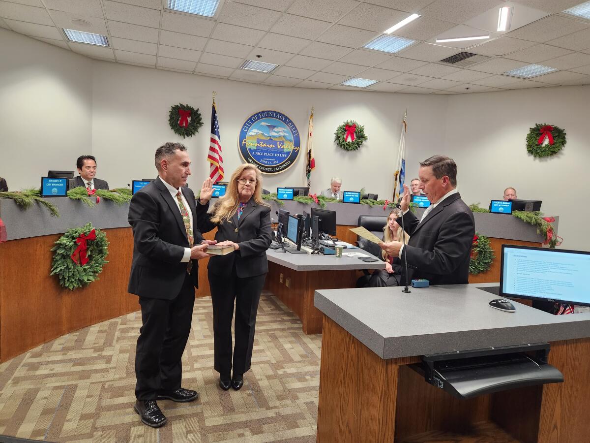 Fountain Valley City Clerk Rick Miller, right, administers the oath of office to Kim Constantine, who is sworn in as mayor.