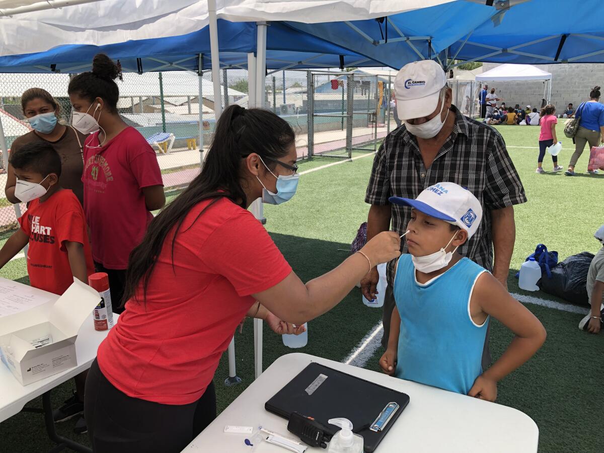 A woman tests a child for the coronavirus as others await their turn