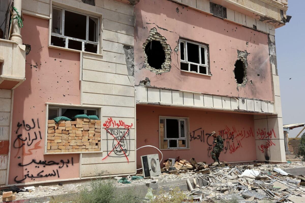 A member of the Iraqi pro-government forces walks past a heavily damaged building Saturday during an offensive to retake the city of Fallouja from Islamic State.