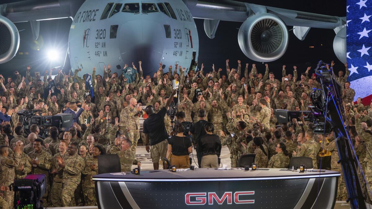 In this handout photo from the U.S. Air Force, American service members participate in a live broadcast with the hosts of Fox NFL Sunday during their Salute to Veterans broadcast, Nov. 13, 2022 at Al-Udeid Air Base in Qatar. As over a million World Cup fans fill stadiums with cheers and carry heady optimism through the streets of Doha, some 8,000 American troops are running air wars in Afghanistan, Iraq, Syria and other hotspots in the Middle East mere miles away. (U.S. Air Force/Airman 1st Class Andrew Britten, via AP)