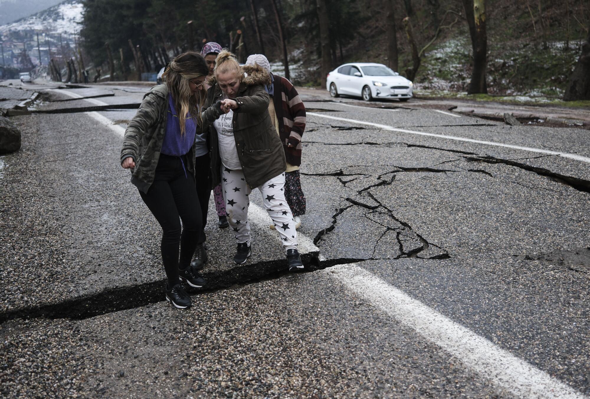 A group of women navigates damaged roads in Fevzipasa, Turkey.