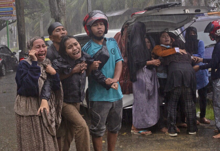 People react as the body of a relative is recovered from the rubble of a building at an area affected by an earthquake in Mamuju, West Sulawesi, Indonesia, Friday, Jan. 15, 2021. A strong, shallow earthquake shook Indonesia's Sulawesi island just after midnight Friday, toppling homes and buildings, triggering landslides. (AP Photo/Yusuf Wahil)