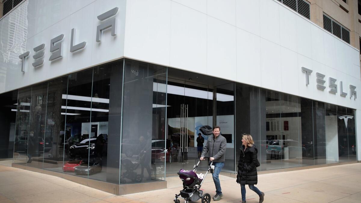 People walk past a Tesla dealership in Chicago.