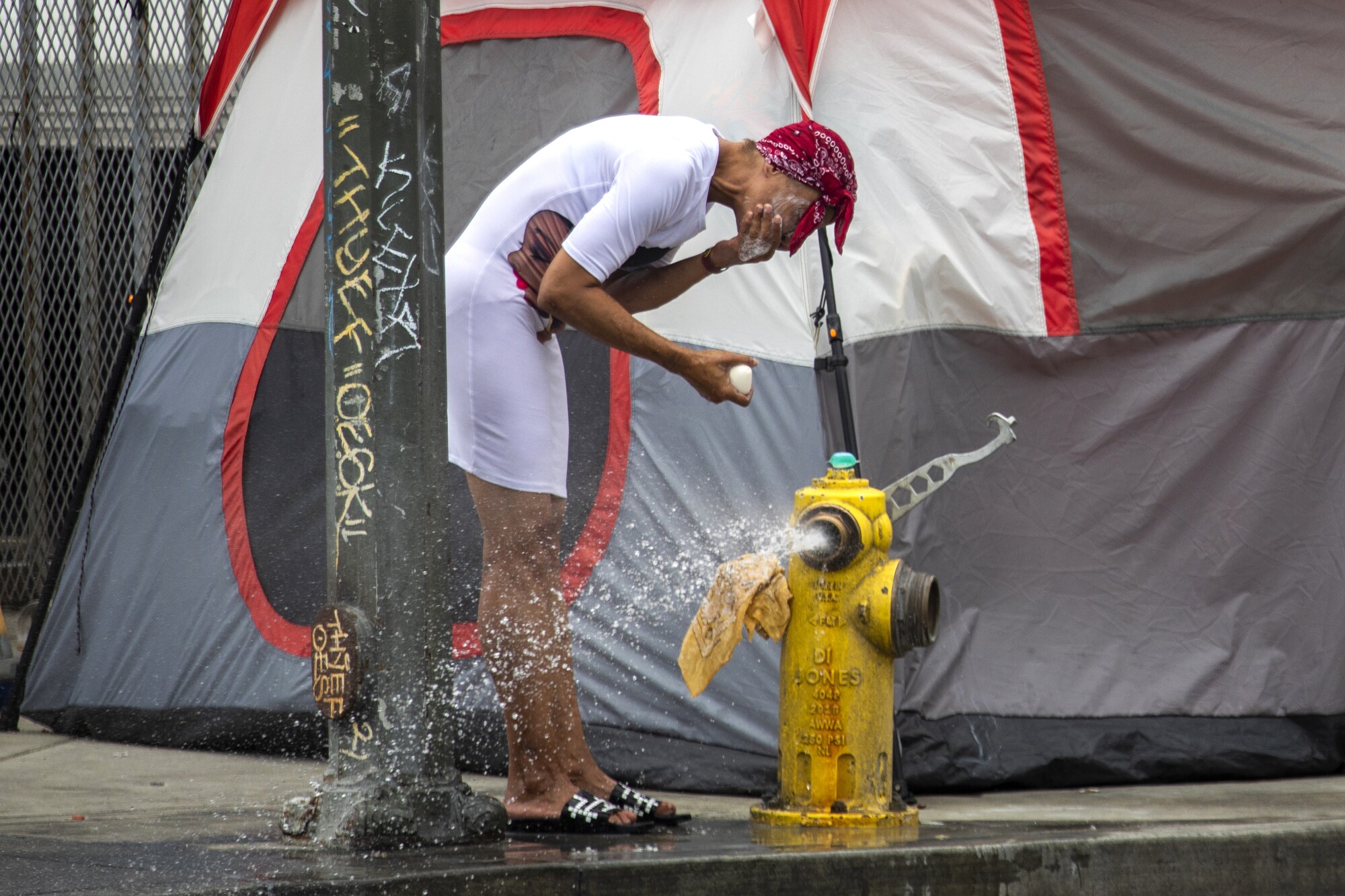 A woman washing her face near a fire hydrant