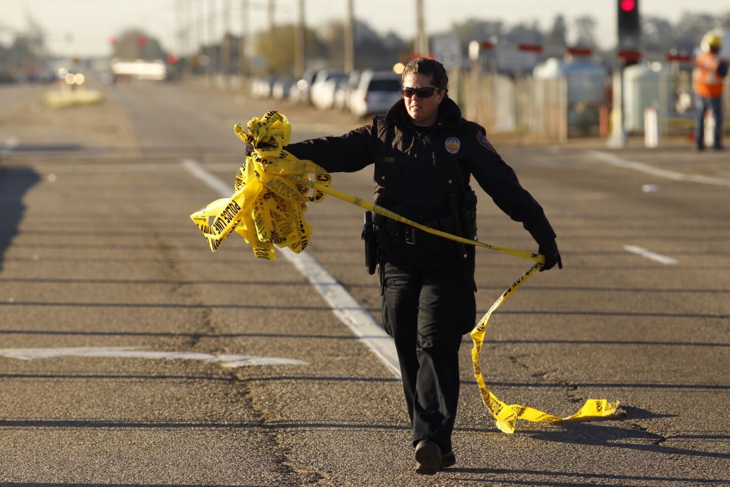 Oxnard police Officer Sarah Shobe removes tape in preparation of reopening Rice Avenue on the morning of Feb. 25, a day after the crash.