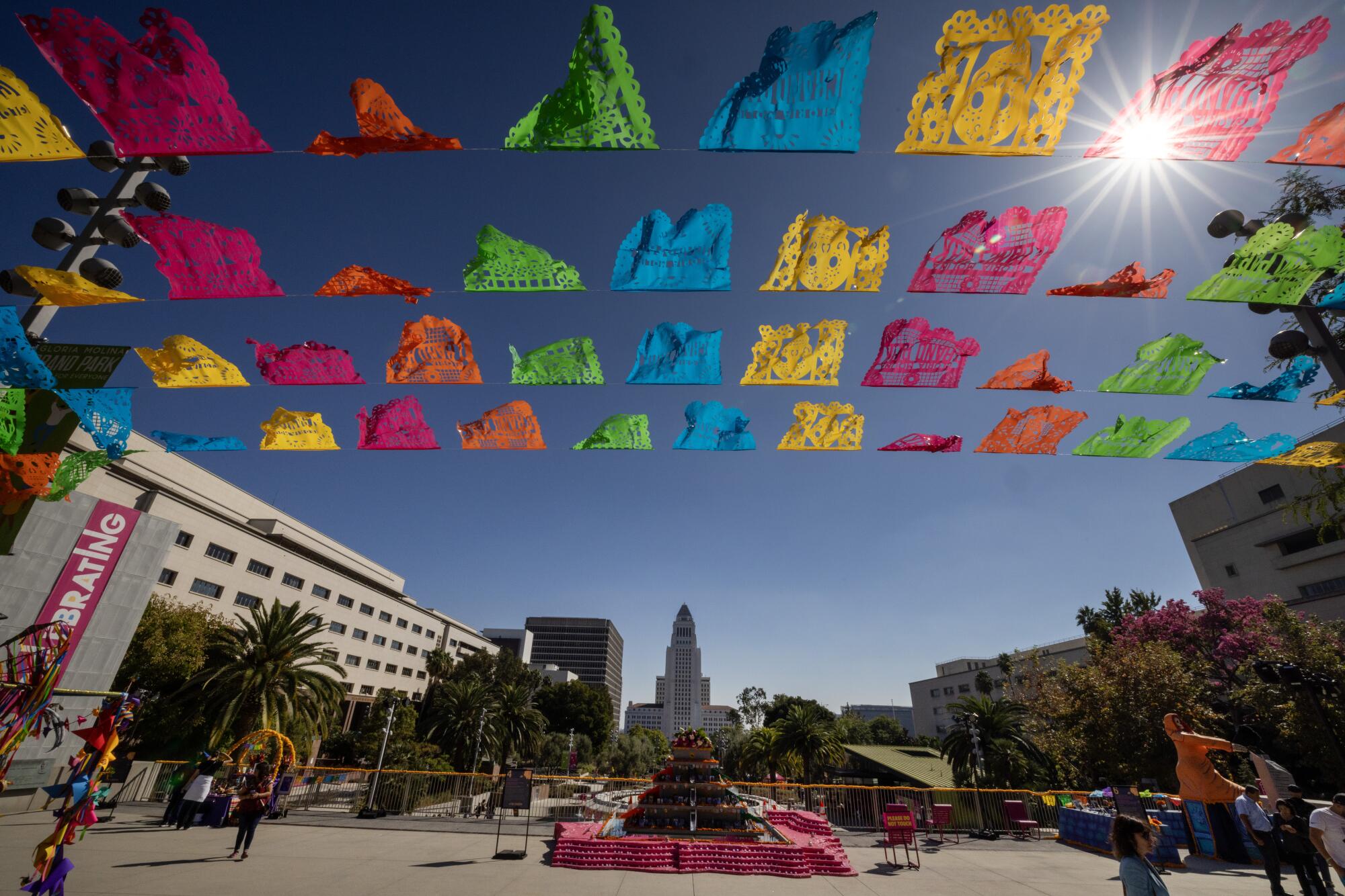 Colorful flags wave in the breeze at Gloria Molina Grand Park's Downtown Dia de los Muertos near altars.