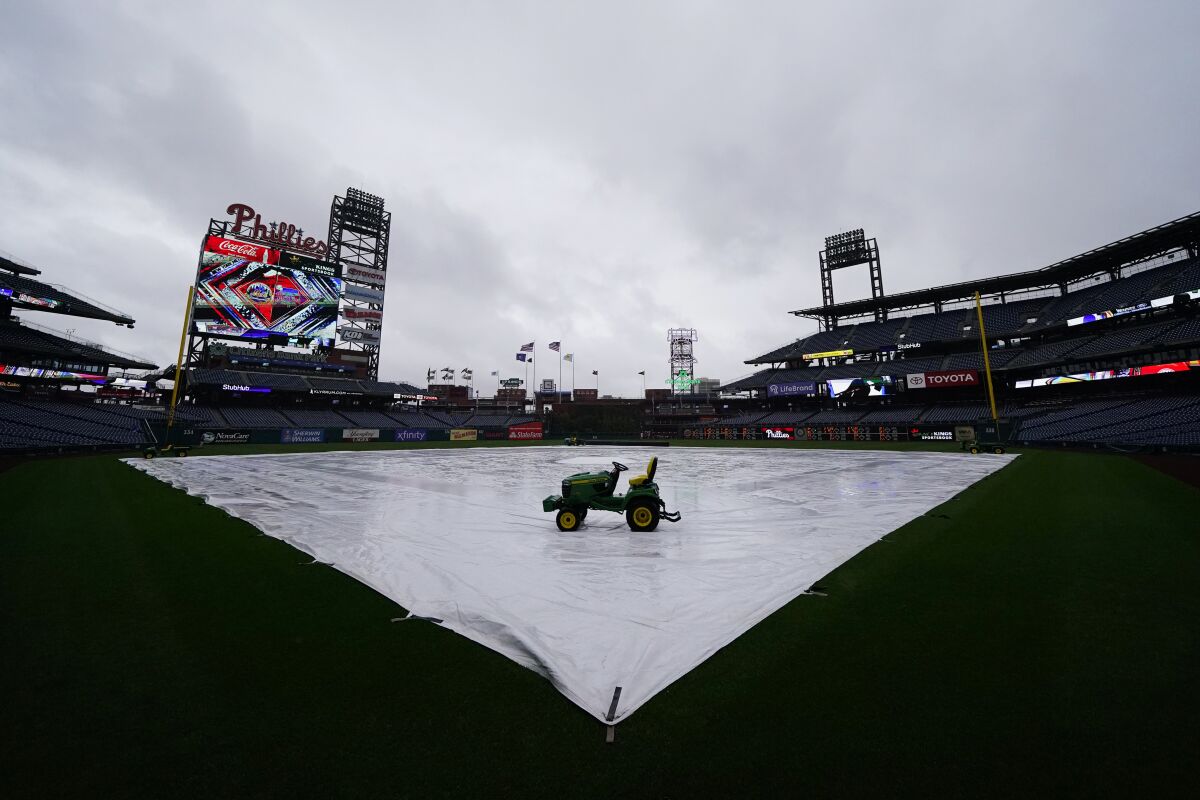 A tarp is seen covering the field as a storm postpones a baseball game between the Philadelphia Phillies and the New York Mets, Saturday, May 7, 2022, in Philadelphia. (AP Photo/Matt Slocum)