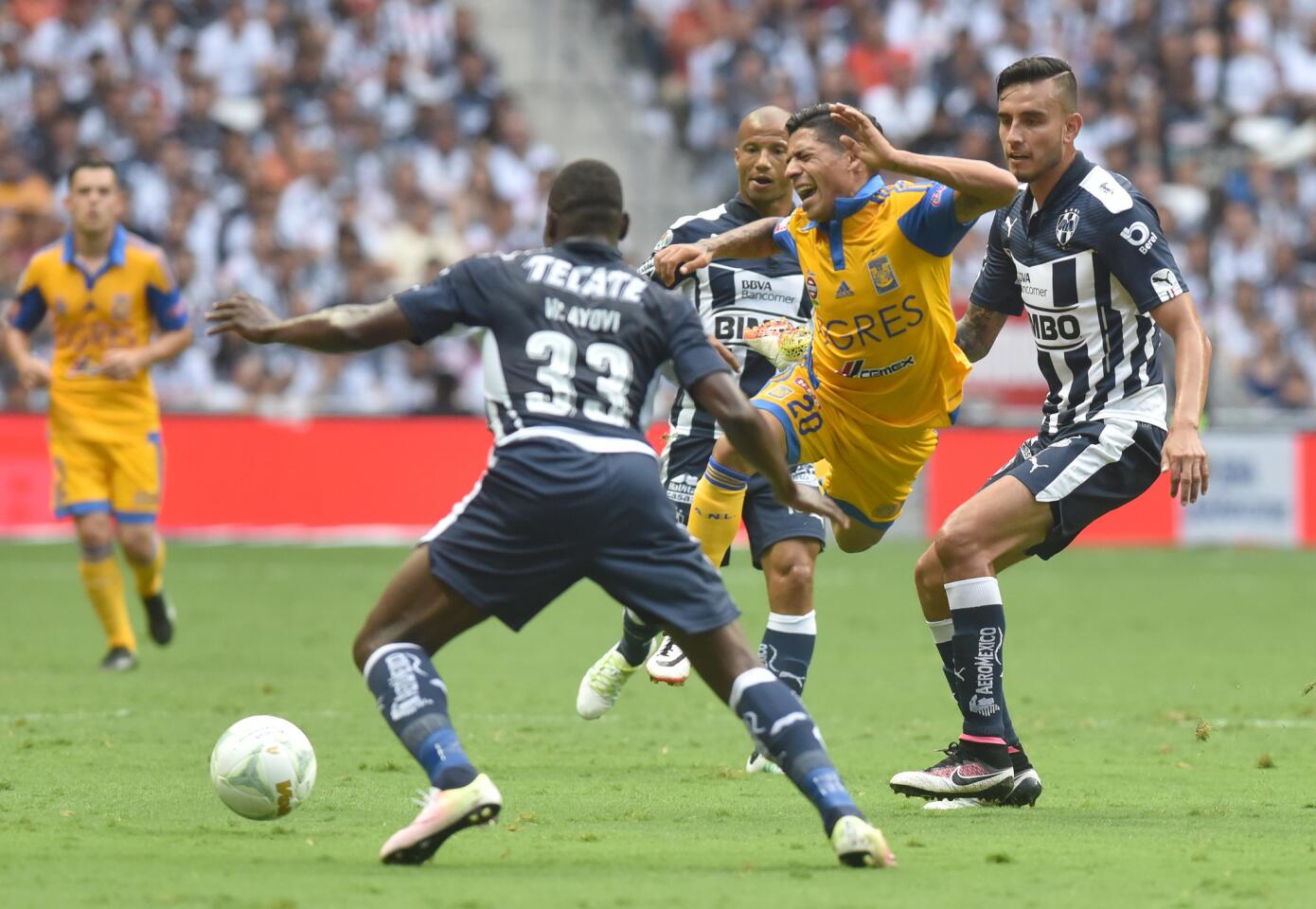 Jesus Zavala (d) de Rayados de Monterrey disputa el balón con Javier Aquino (c) de Tigres, durante el partido correspondiente al partido de vuelta de los cuartos de final del Torneo Clausura 2016 celebrado en el estadio BBVA de Monterrey.