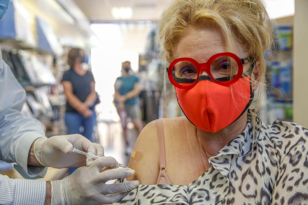 A masked woman gets a flu shot as well as a COVID-19 booster shot.