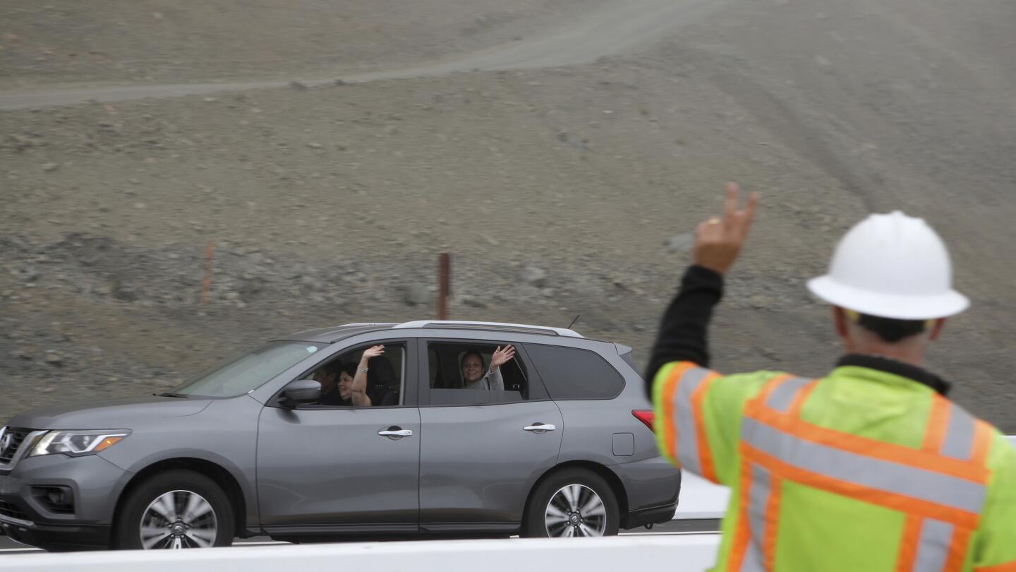 CalTrans construction engineer Wayne Walker waves to a car full of happy travelers as they drive on the newly opened section of Highway 1.