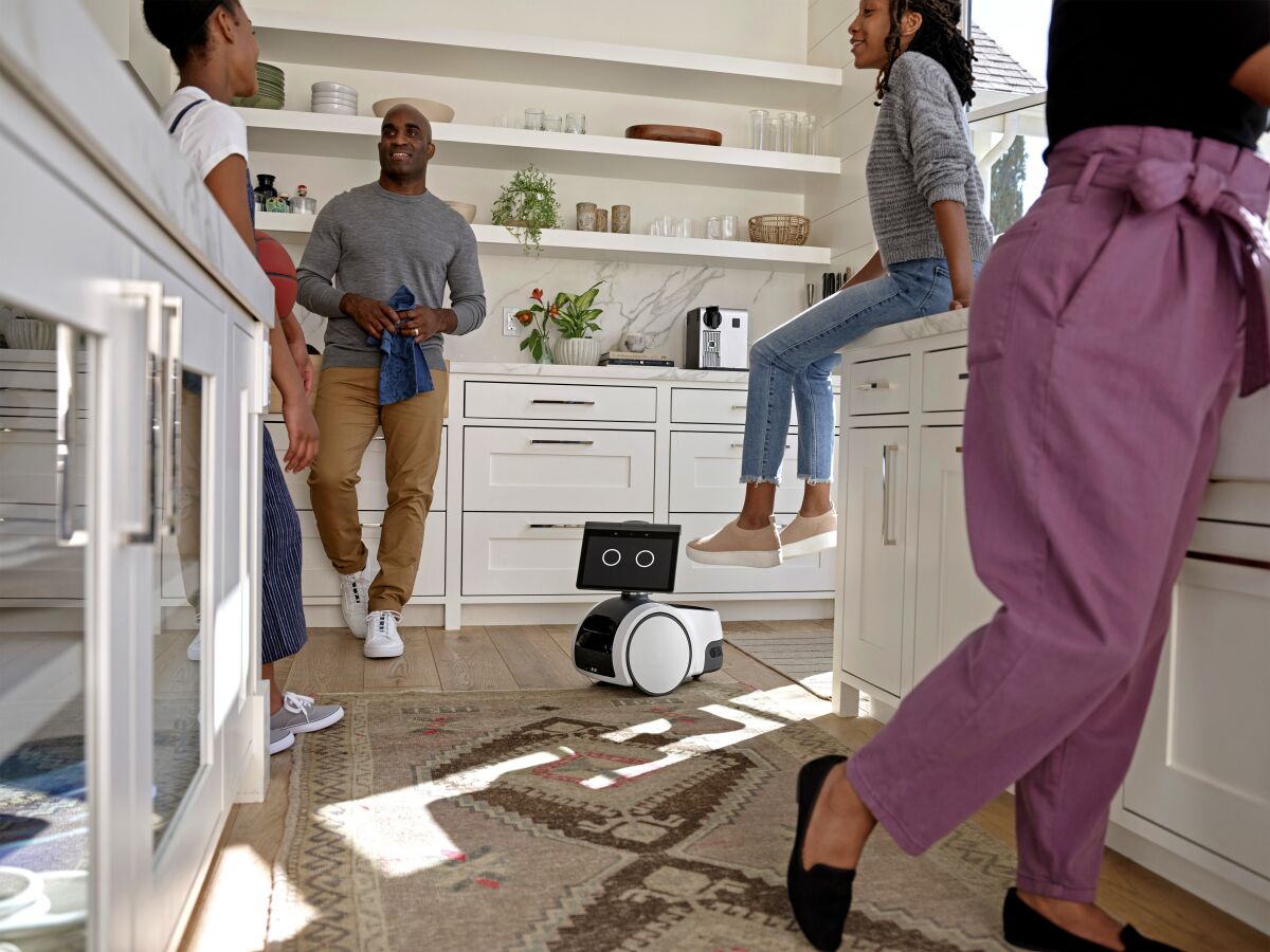 People hanging out in a kitchen with Amazon's robot, Astro, on the floor.
