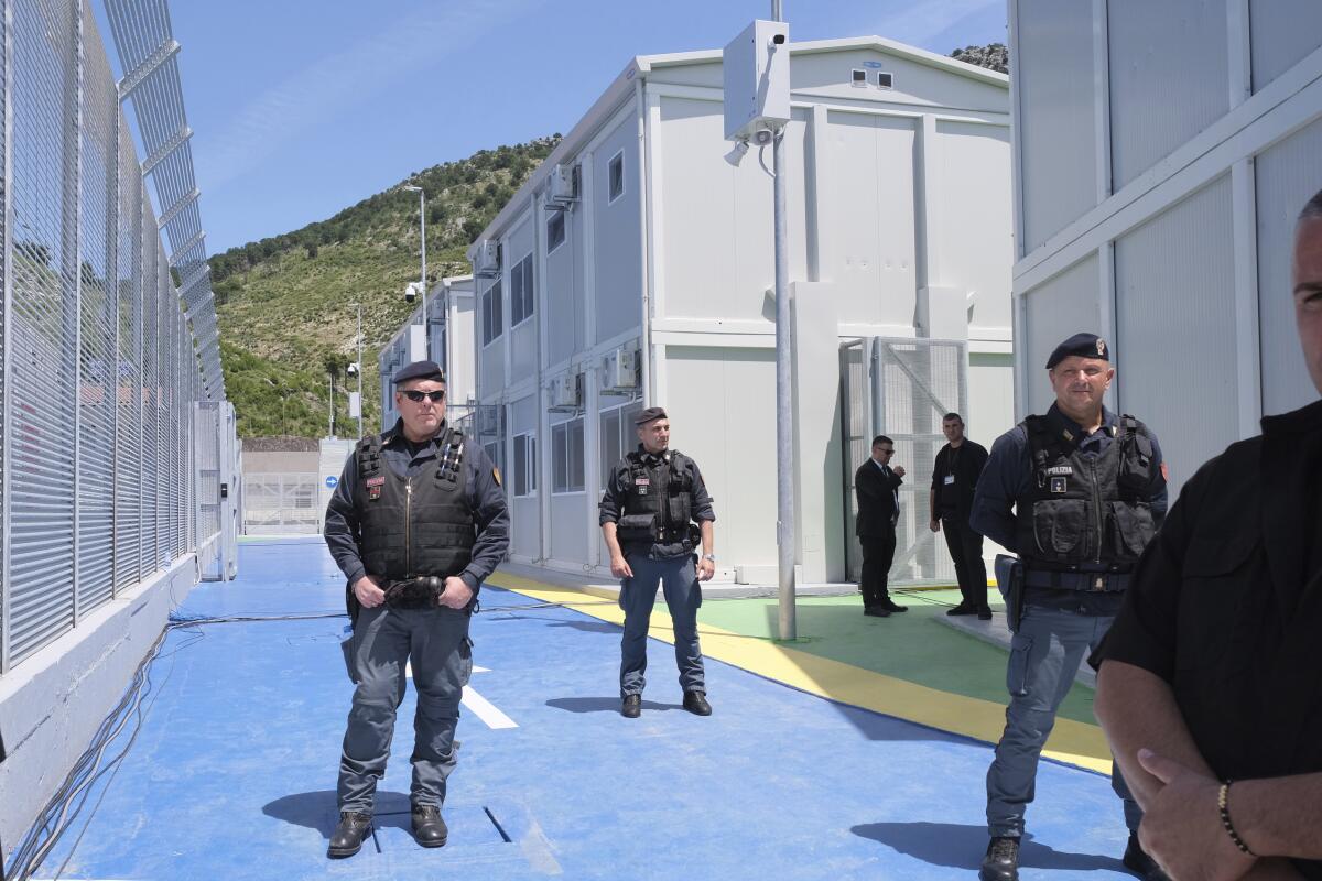 Policemen guard a holding center for migrants.