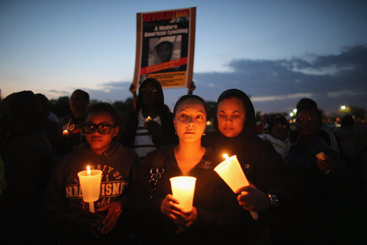 Apollonia Mitchell, Shenika Mitchell and Yolanda Pearson, from left, gather with others for a candlelight vigil at Fort Mellon Park in Sanford, Fla. to mark the one year anniversary of when Trayvon Martin was killed.