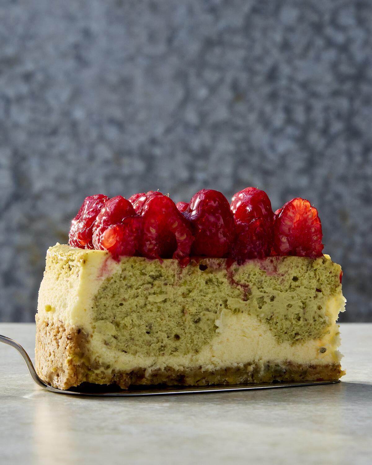 A pistachio cheesecake with raspberry.