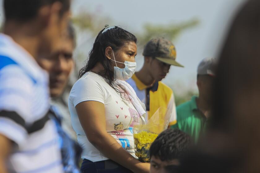A woman wears a mask against the spread of COVID-19 disease, as she attends a funeral at the Central cemetery of Managua, Nicaragua, Monday, May 11, 2020. President Daniel Ortega's government has stood out for its refusal to impose measures to halt the new coronavirus for more than two months since the disease was first diagnosed in Nicaragua. Now, doctors and family members of apparent victims say, the government has gone from denying the disease's presence in the country to actively trying to conceal its spread. (AP Photo/Alfredo Zuniga)