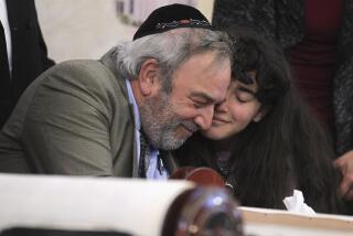 Howard Kaye, center, and his daughter Hannah Kaye hug after the final letter was inked into the new torah that's dedicated to wife and mother Lori Gilbert-Kaye, who was killed when a gunman attacked last April, during a celebration for the new torah at Chabad of Poway on Wednesday, May 22, 2019 in Poway, California.
