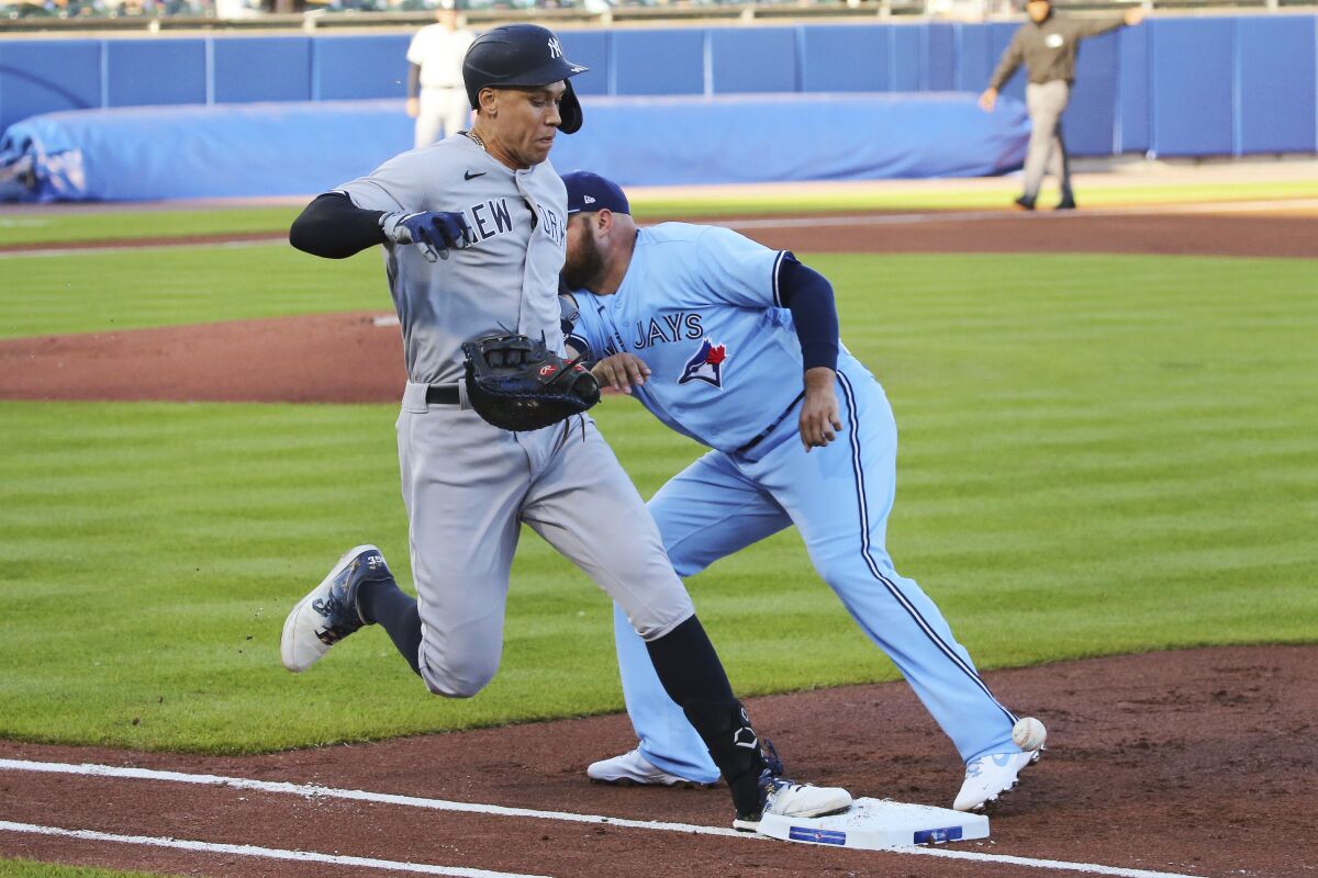 Toronto Blue Jays first baseman Rowdy Tellez loses his glove as New York Yankees' Aaron Judge is safe during the first inning of a baseball game, Thursday, June 17, 2021, in Buffalo, N.Y. (AP Photo/Jeffrey T. Barnes)