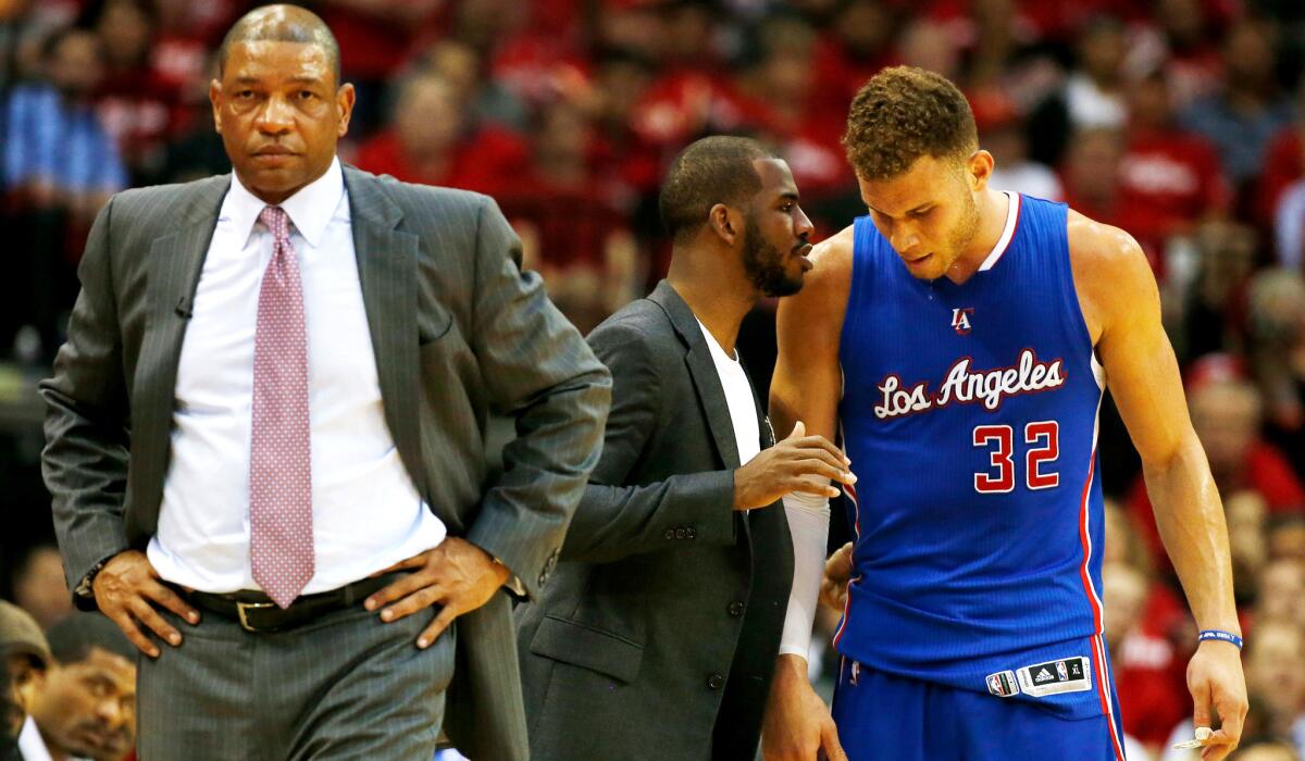 Clippers Coach Doc Rivers strolls the sideline as injured point guard Chris Paul, center, talks to forward Blake Griffin (32) during a break in the second half of Game 2.