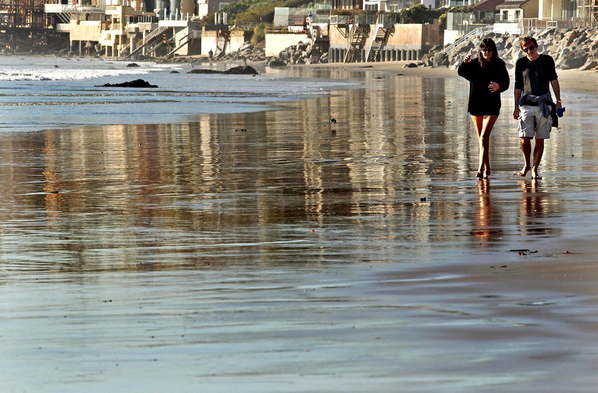 Nadine Froger, left, and Jean Jacques Pochet walk along Broad Beach in Malibu.