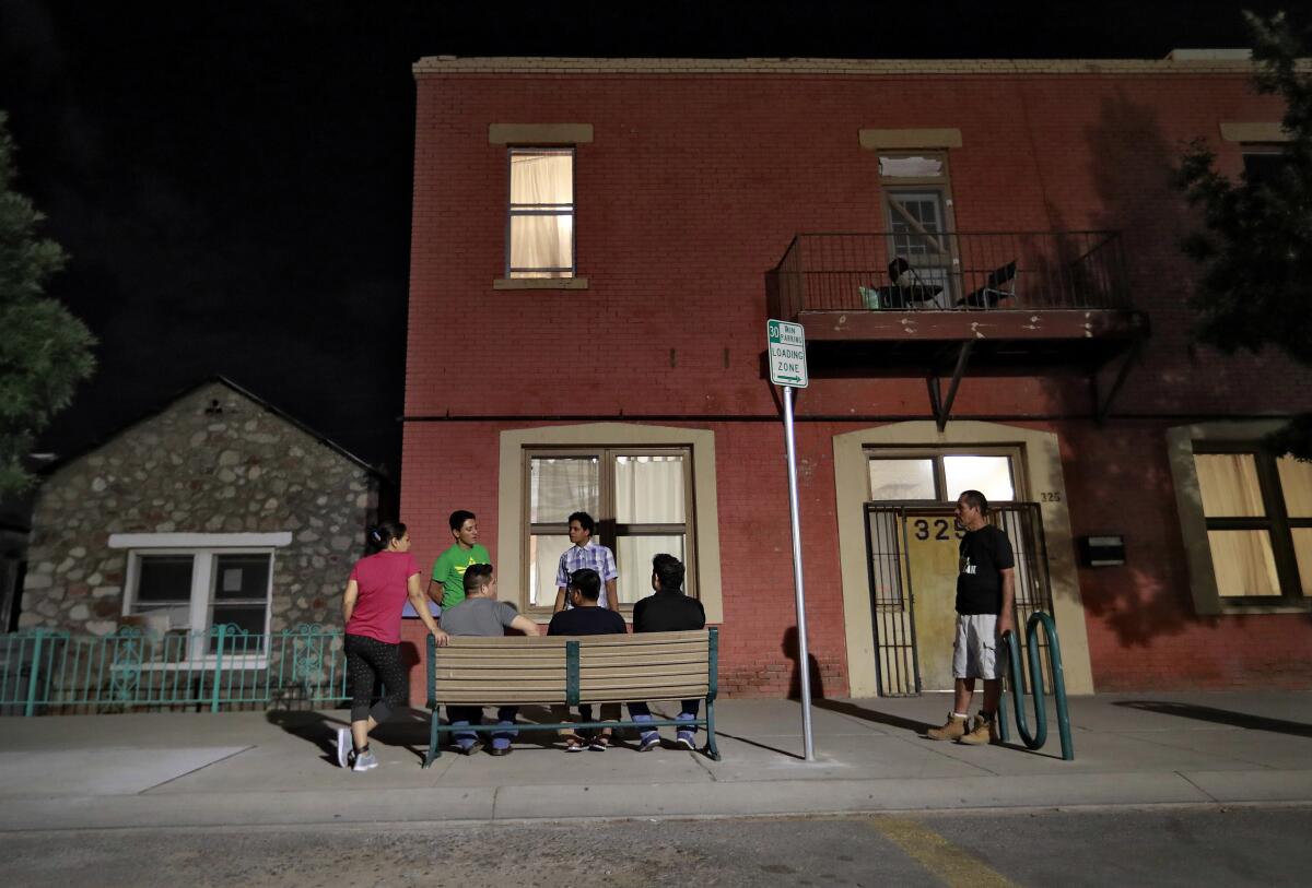 Migrant parents sitting and standing outside a building