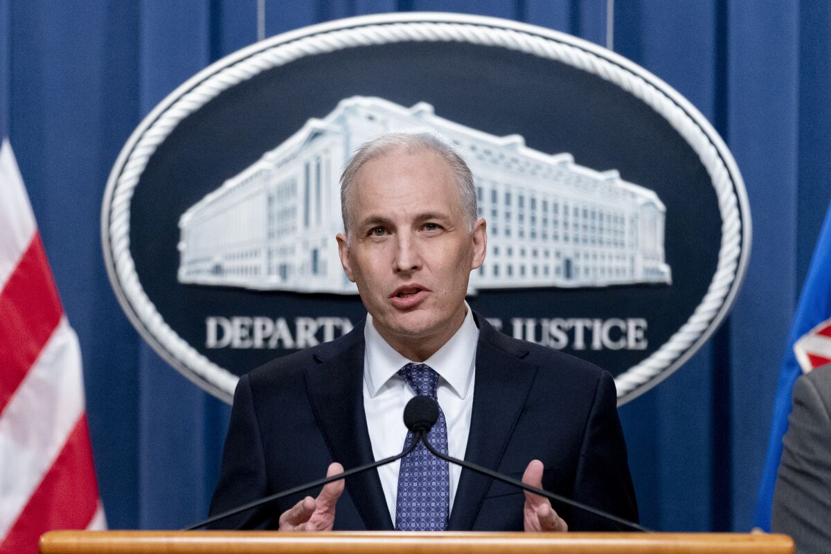 Justice Department's Assistant Attorney General for the National Security Division Matthew Olsen, left, speaks at a news conference at the Justice Department in Washington, Wednesday, March 16, 2022, to discuss recent law enforcement actions to address transnational repression. The Justice Department says a Chinese operative sought to undermine the congressional candidacy of a Chinese dissident in New York, including by seeking to uncover or even manufacture derogatory information that would cause him to lose the race. (AP Photo/Andrew Harnik)