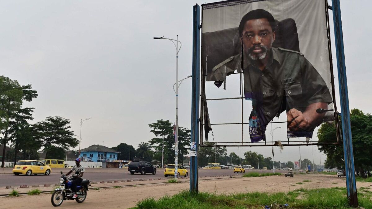 A torn portrait of Congolese President Joseph Kabila stands next to a Kinshasa roadway this week. The strongman is accused of making a backroom deal with candidate Felix Tshisekedi to put Tshisekedi in office when the ruling party did poorly at the polls.