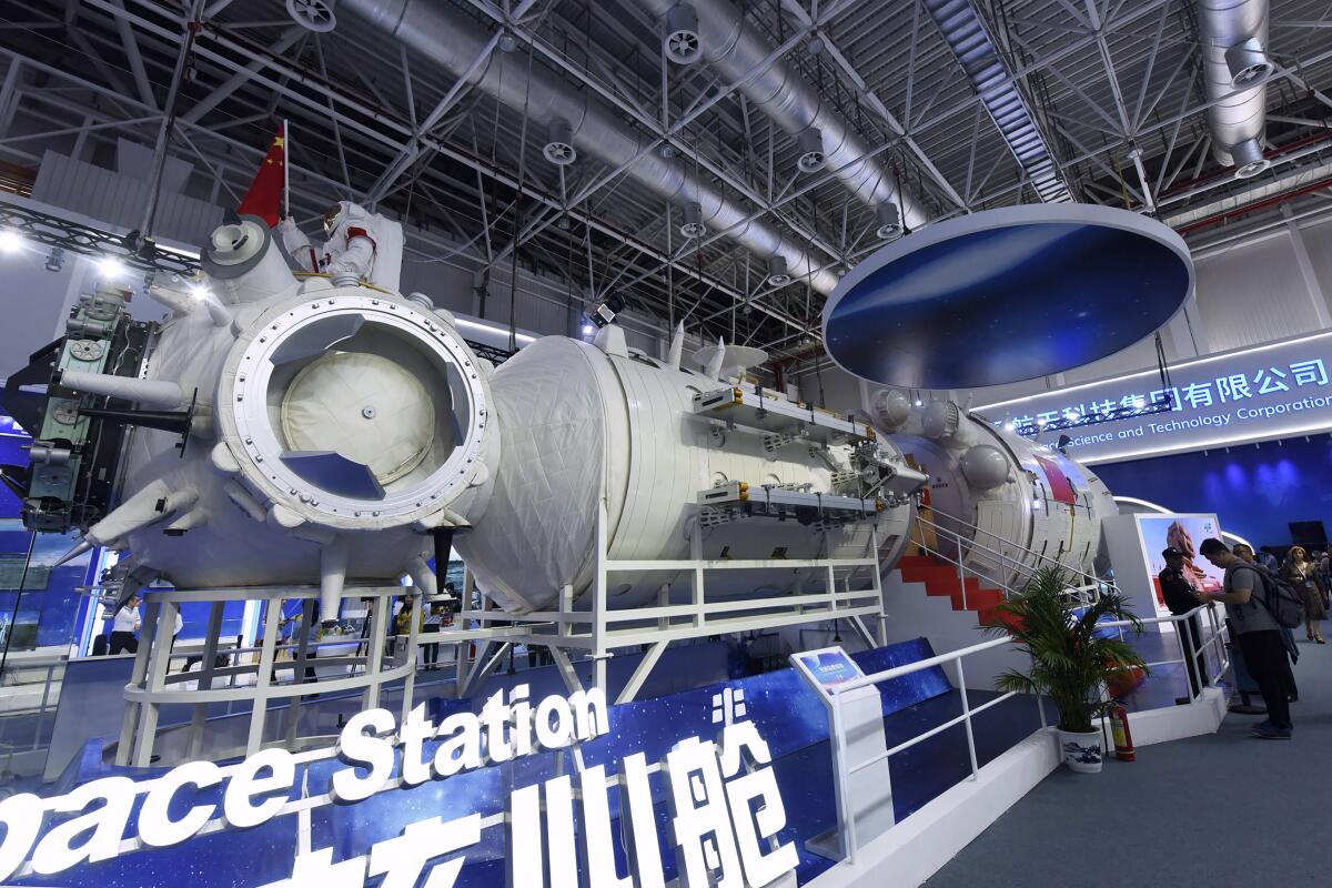 Visitors look at a life-size model of the Tianhe core module of China's space station