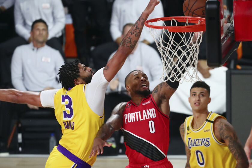 Lakers forward Anthony Davis, left, blocks a shot by Portland Trail Blazers guard Damian Lillard during Game 2.