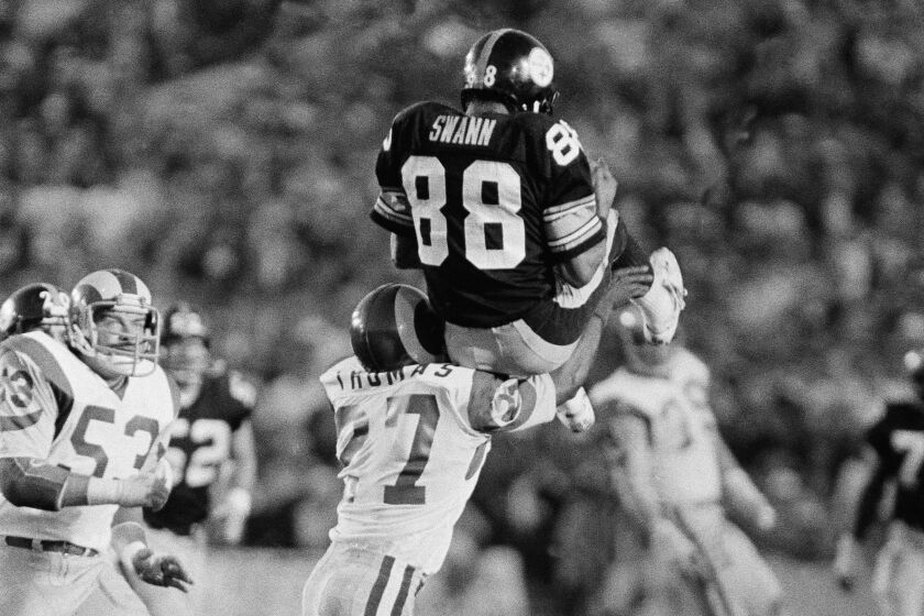Pittsburgh Steelers receiver Lynn Swann (88) rests briefly on shoulder of Los Angeles Rams defender.