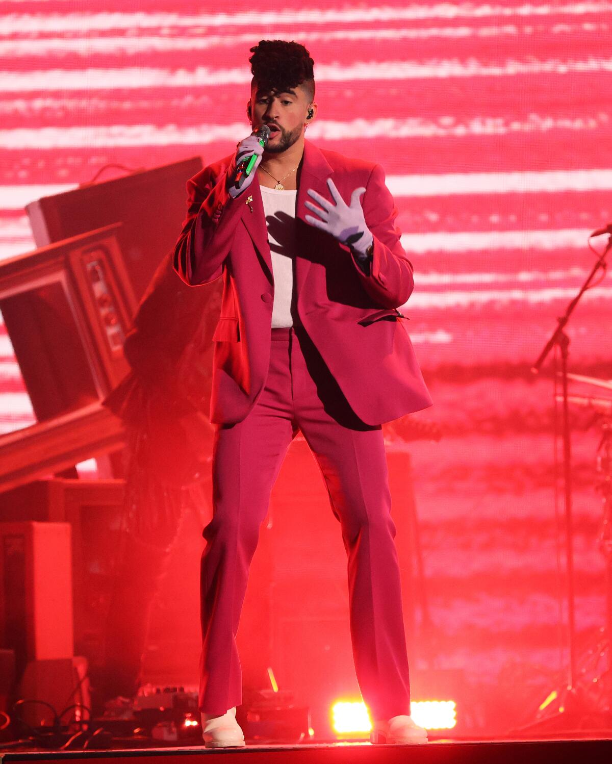 A man in a red suit performs onstage