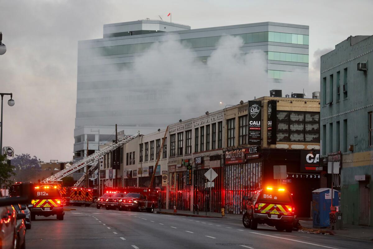 Firefighters battle a fire at the scene of an explosion and fire Saturday in the 300 block of Boyd Street in downtown Los Angeles. Twelve firefighters were injured in the blast.
