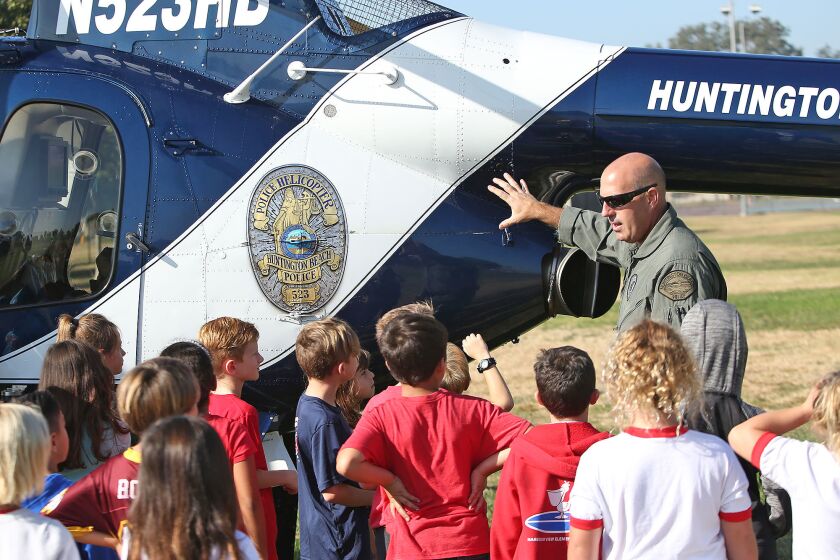 The Huntington Beach police helicopter pilot Tyler Hanson is the center of attention during First Responders Fair and patriotic assembly at Harbor View Elementary school on Friday. Members of local law enforcement agencies, including Huntington Beach, shared their job duties and equipment with kids for an early Veterans Day celebration.
