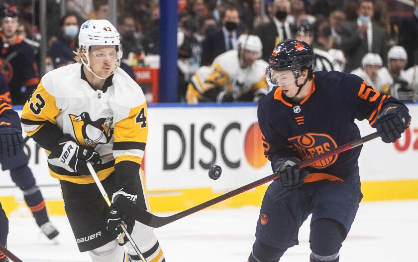 Pittsburgh Penguins' Danton Heinen (43) and Edmonton Oilers' Kailer Yamamoto (56) vie for the puck during the first period of an NHL hockey game Wednesday, Dec 1, 2021, in Edmonton, Alberta. (Jason Franson/The Canadian Press via AP)