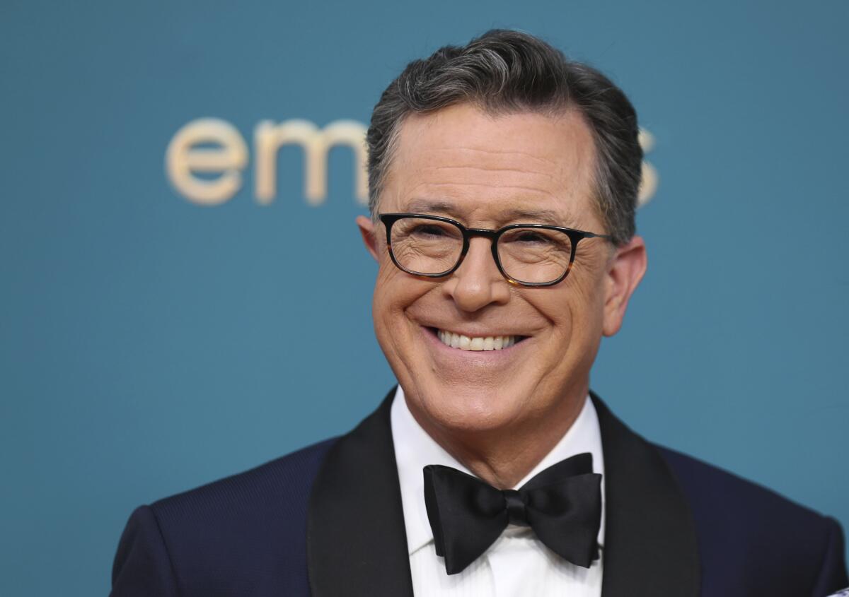 Stephen Colbert smiles in his signature eyeglasses and a black bowtie and tuxedo