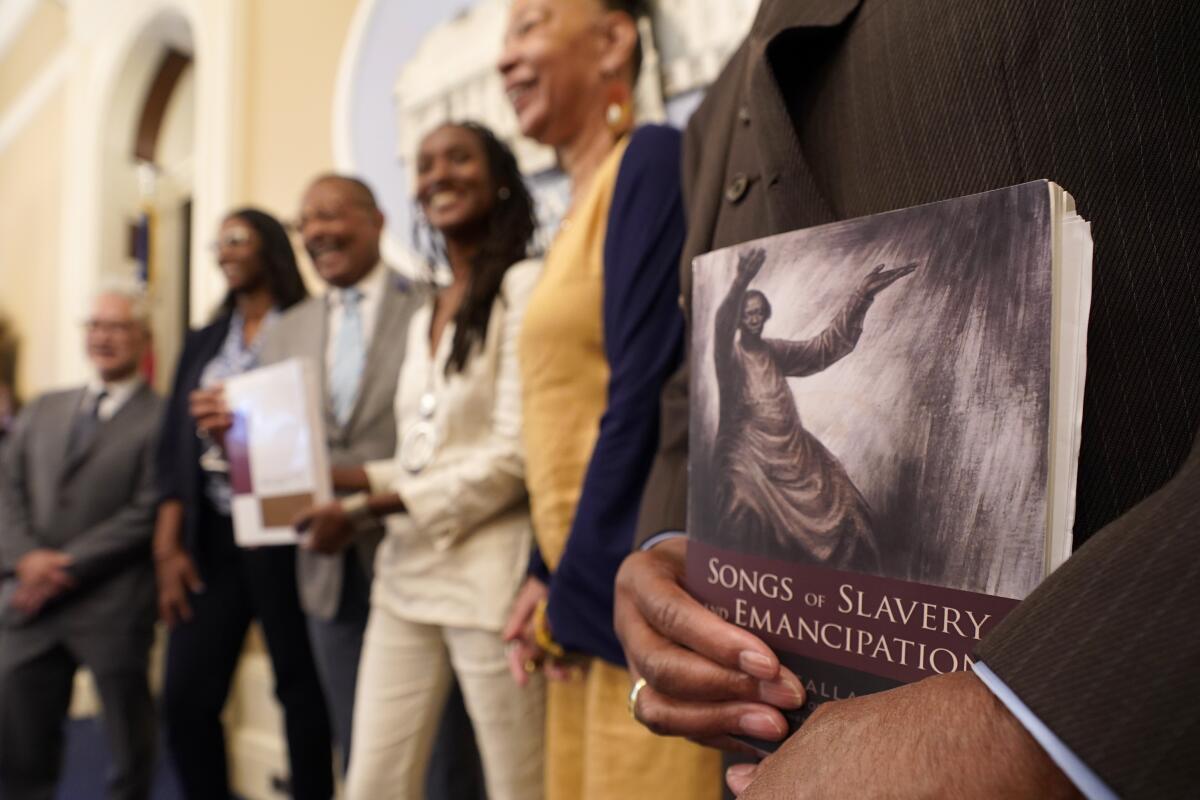 A man holds a copy of the book "Songs of Slavery and Emancipation" during a group photo.