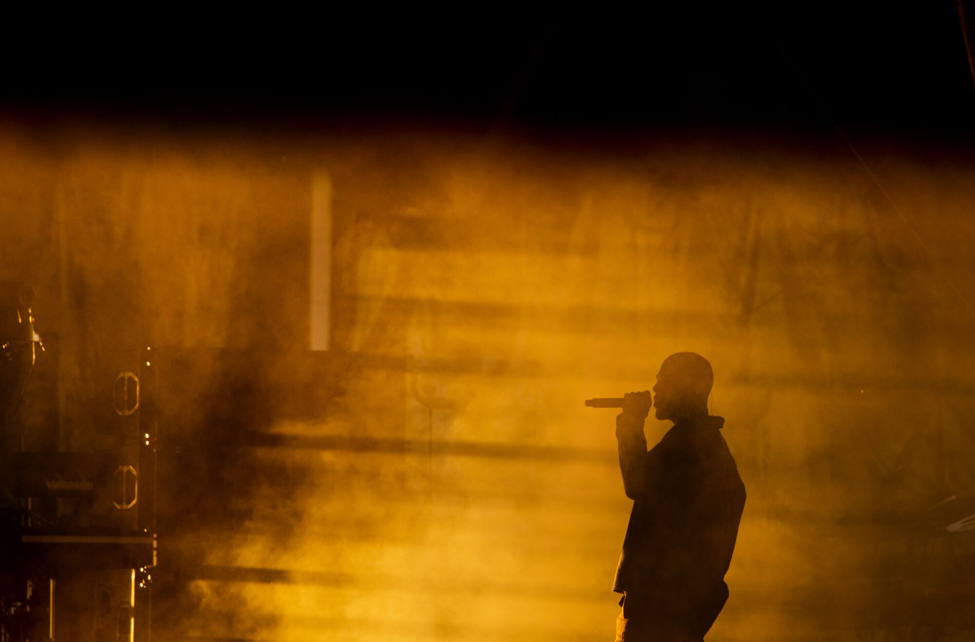 A silhouette of a man with a microphone to his face 
