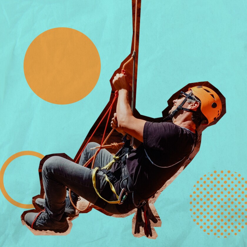 A man wearing a helmet holds onto a rope.