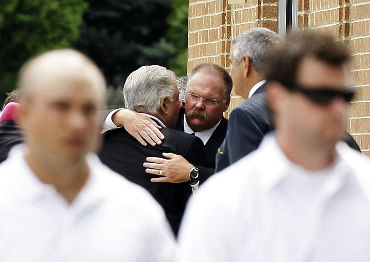 Andy Reid, center, is embraced after the funeral for his son Garrett Reid in Broomall, Pa., in August 2012.