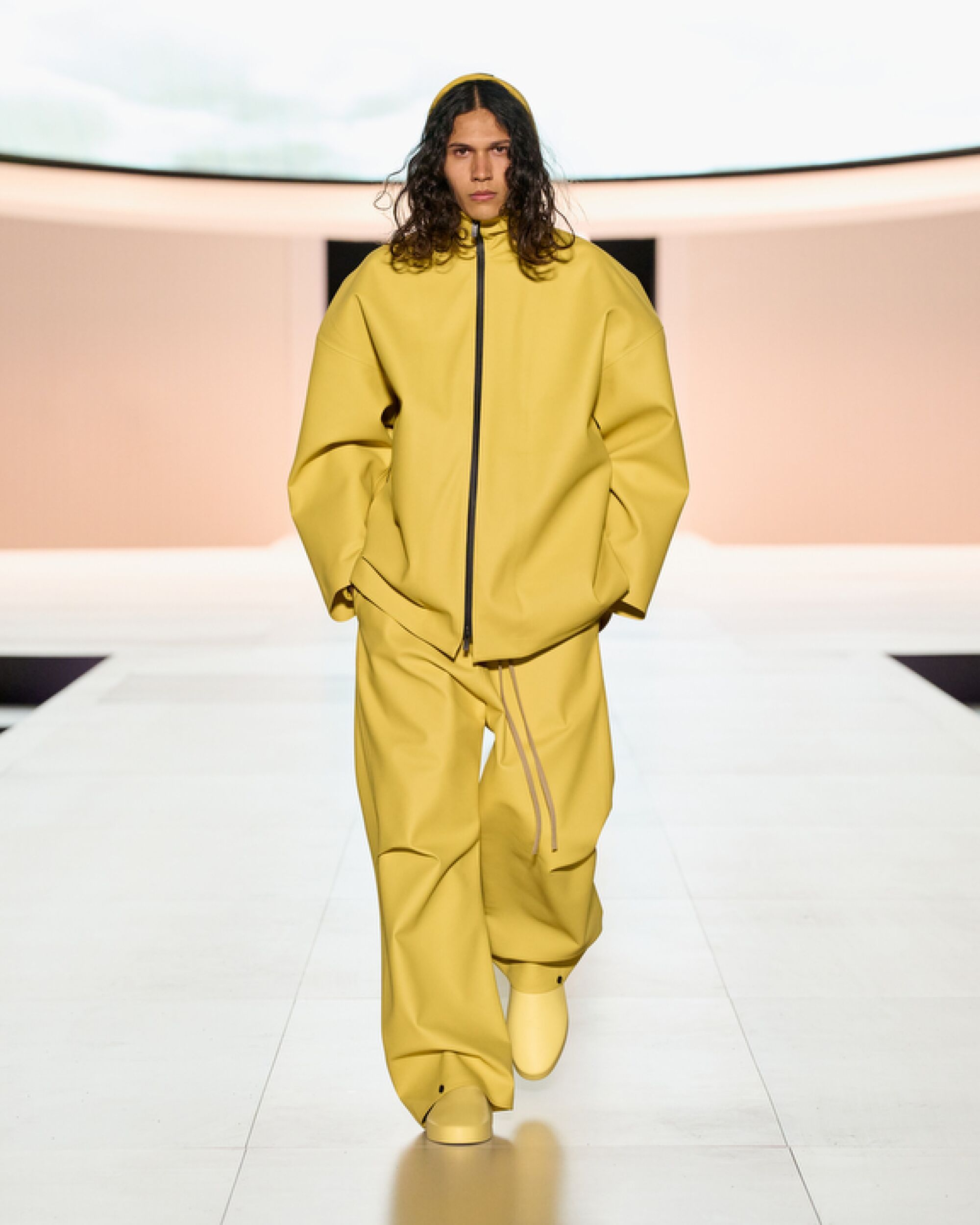 Model wears yellow Fear of God outfit on runway.