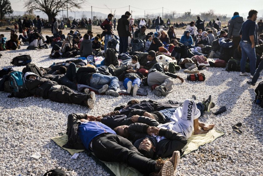 Migrants and refugees, many of them Syrian, rest on the ground as they wait to enter a registration camp after crossing the Greek-Macedonian border on Nov. 18.