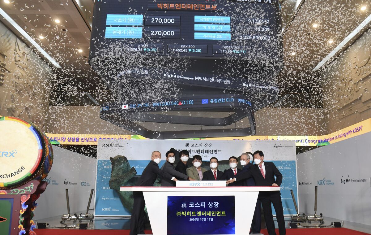 Big Hit Entertainment Ltd.’s Chairman and CEO Bang Si-Hyuk, fourth from left, poses with other participants for the media during the listing ceremony of the company at the Korea Exchange in Seoul, South Korea, Thursday, Oct. 15, 2020. The company, that manages boy band BTS made its market debut amid criticism by Chinese internet users after the group’s leader thanked Korean War veterans for their sacrifices. (Korea Pool/Yonhap via AP)