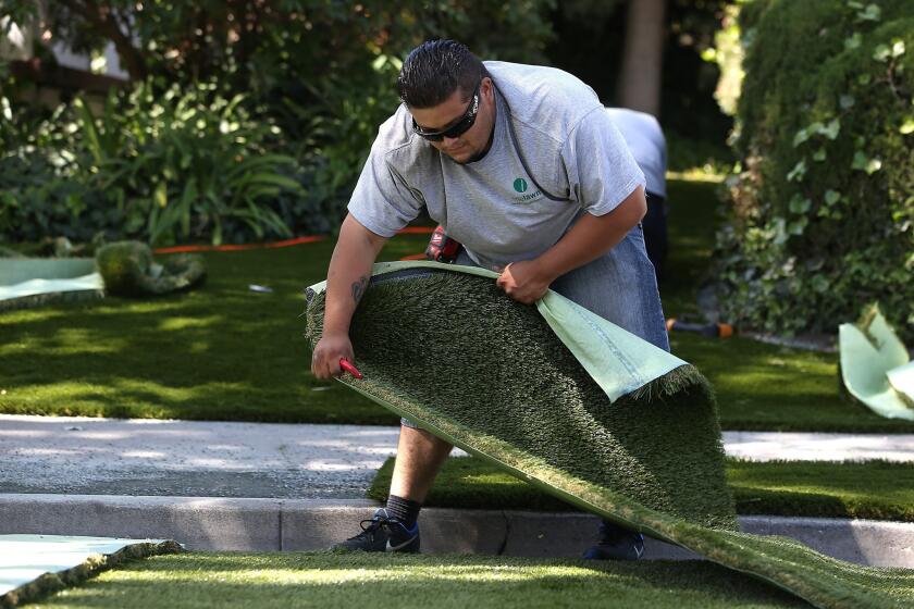 Juan Martinez of landscaping company Onelawn installs a section of artificial lawn at a home in Burlingame, Calif.