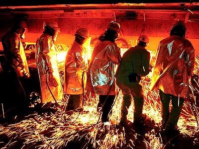Casters work to clear the way for molten steel.