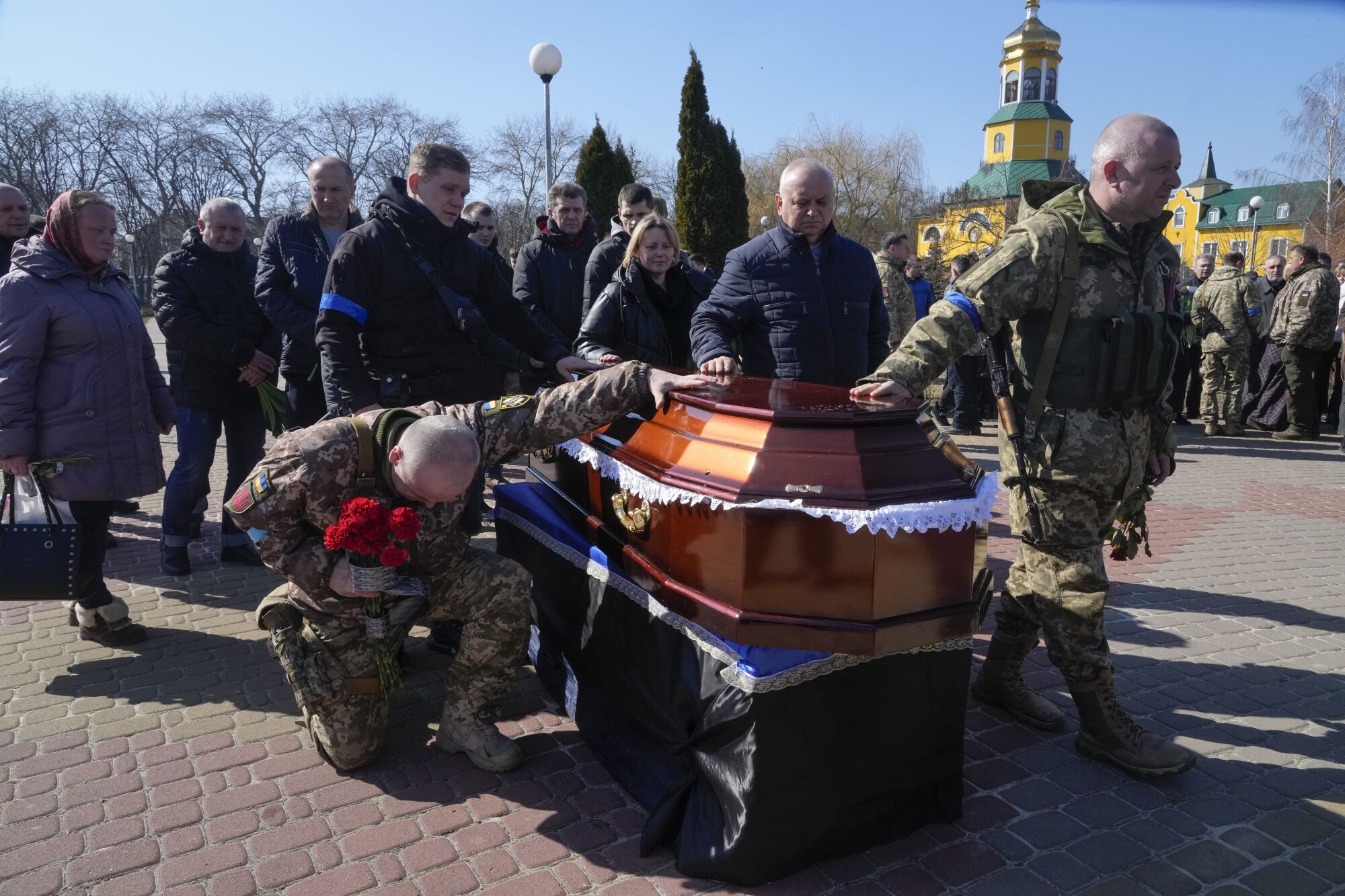 A Ukrainian soldier prays by a casket.