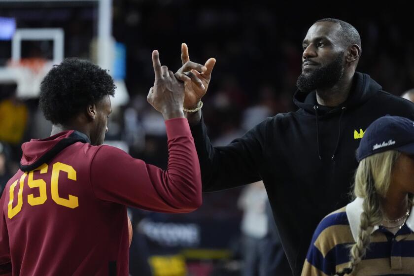 Southern California guard Bronny James, left, high-fives his father, Los Angeles Lakers' LeBron James, as he warms up before an NCAA college basketball game against Stanford in Los Angeles, Saturday, Jan. 6, 2024. (AP Photo/Ashley Landis)