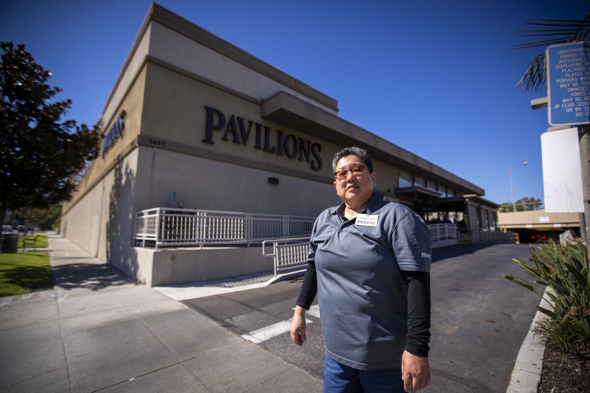 A woman stands outside a Pavilions grocery store.