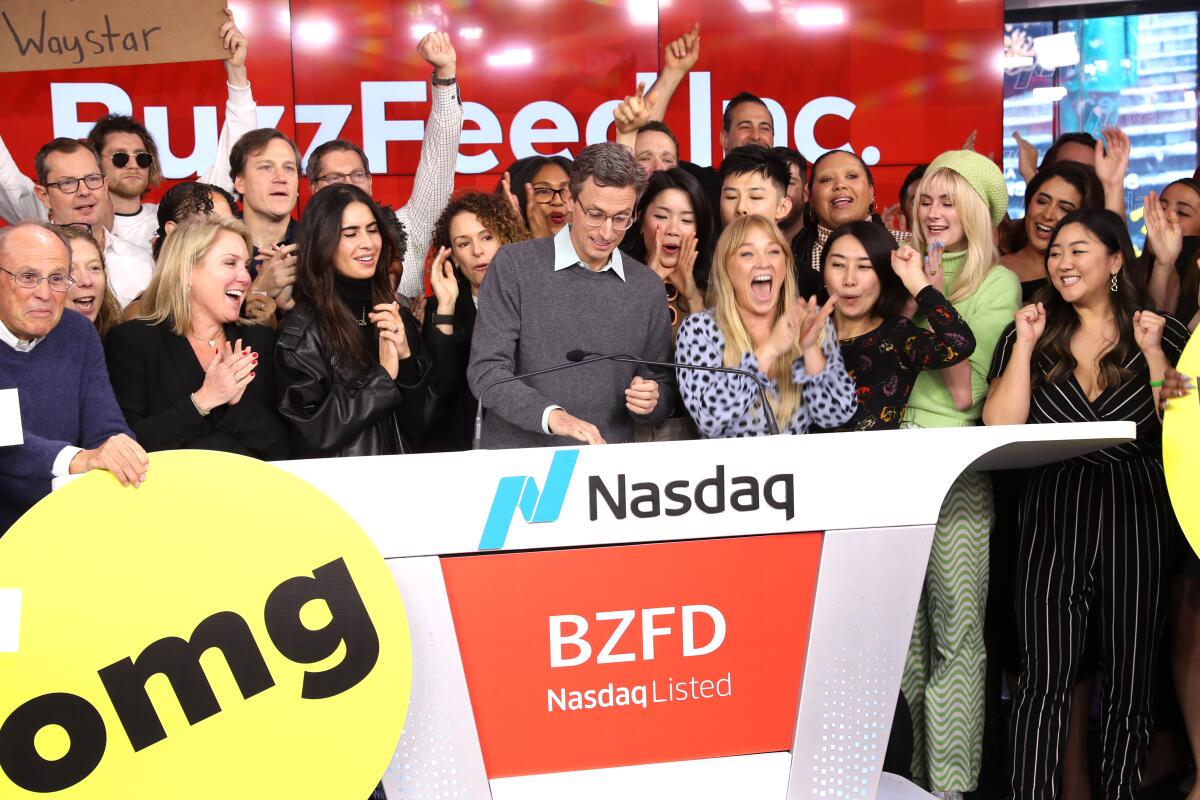 a crowd of people with a man at center in front of a wall with BuzzFeed Inc. logo 